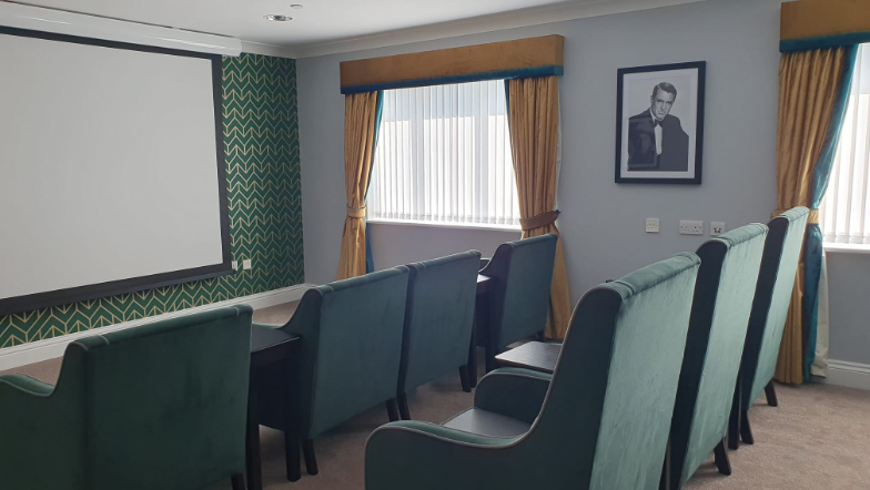 front facing view of our cinema room from the side including the screen and chairs