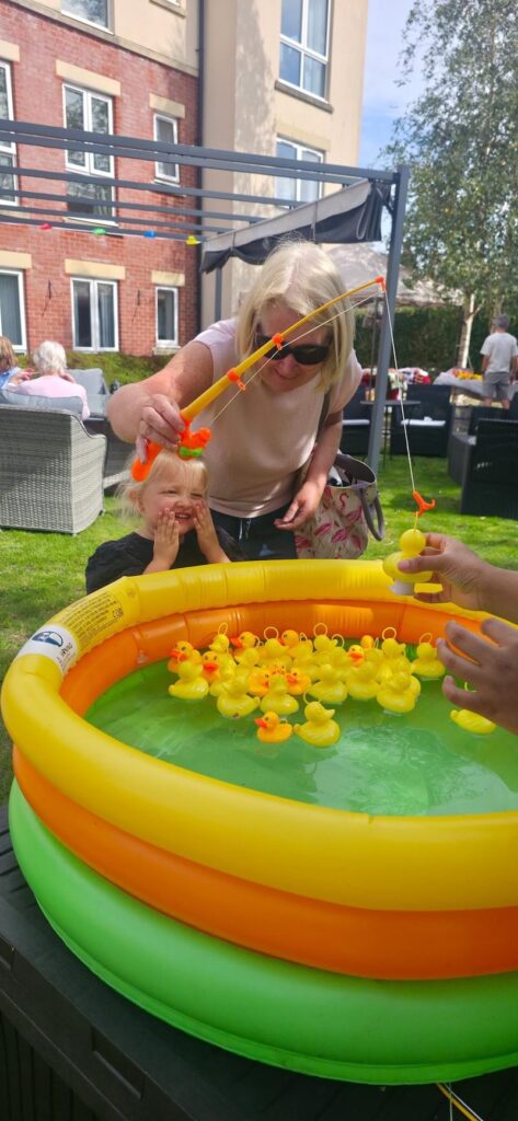 a young girl playing hook a duck with her parent