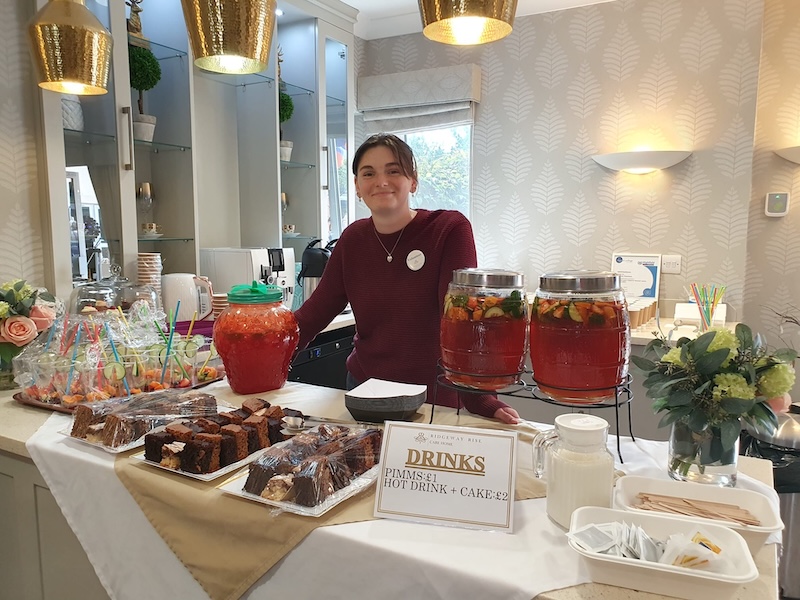 one of our team offering pimms and snacks on a table