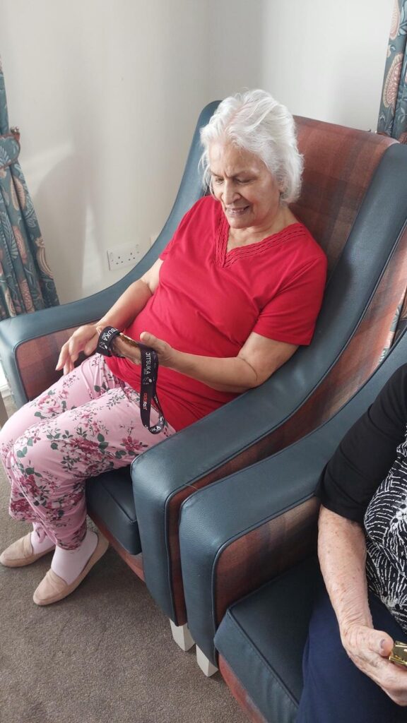 female resident sat down in an armchair looking at a medal in her hand