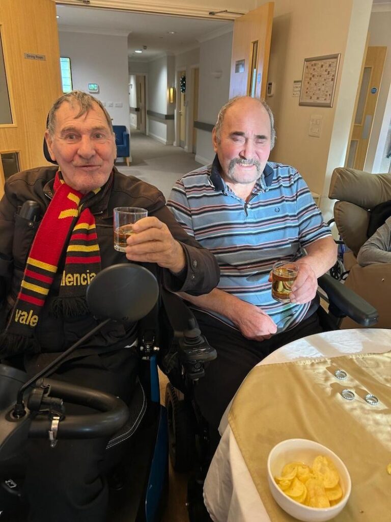 two male residents sat together smiling and enjoying a drink