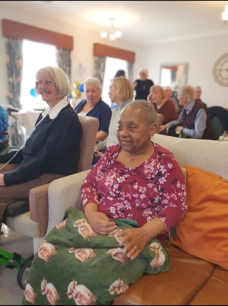 one of our residents wearing a floral top smiling in the lounge