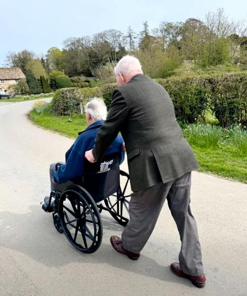 older man pushing another older man in a wheelchair