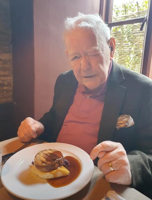 older man with a plate of food on a table