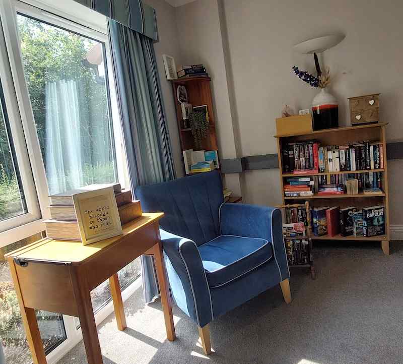 our library destination point with a blue armchair and bookshelf with a variety of books