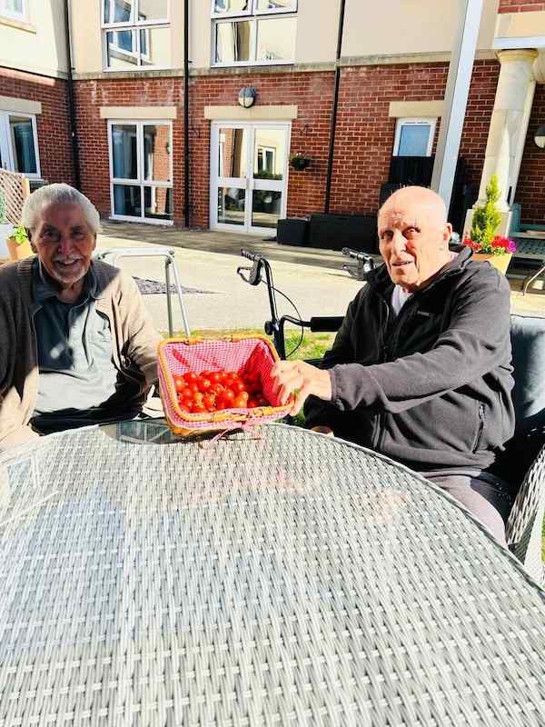 two residents sitting outside with tomatoes